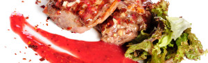 Grilled pork steaks with raspberry sauce and leaf of lettuce